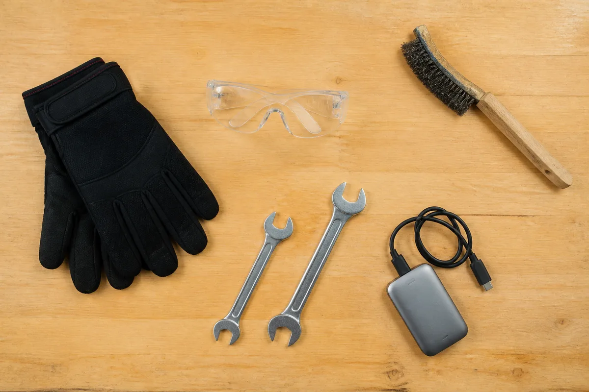 Gants, lunettes de protection, clés plates et boîtier de sauvegarde mémoire posés sur un établi