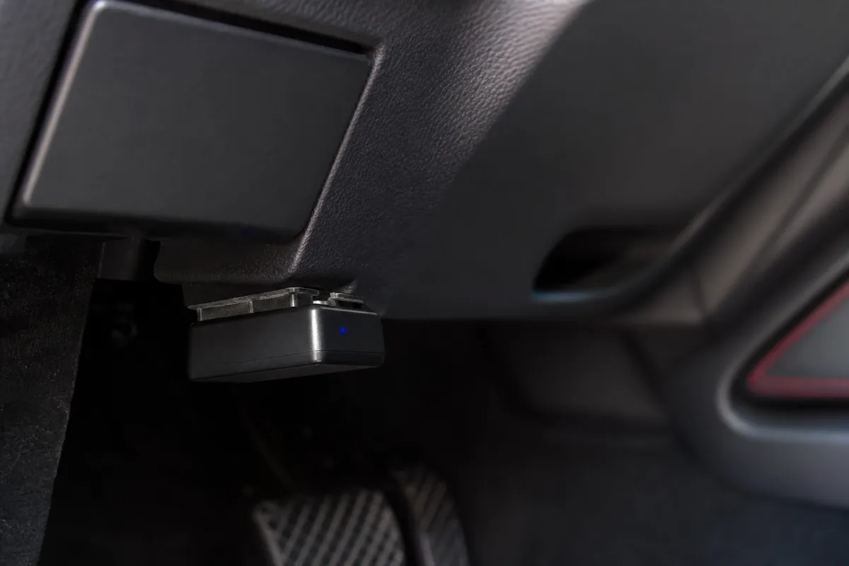 Lecteur de diagnostic OBD branché sur la prise située sous le volant d’une voiture